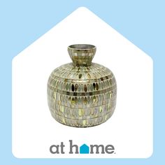 a decorative glass vase sitting on top of a blue and white background with the words at home above it