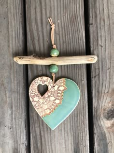 a wooden heart hanging on a piece of wood next to a beaded necklace with green beads