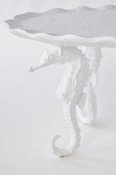 a white table with a sea horse on it's legs and a tray underneath it