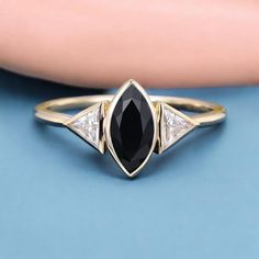 a black and white diamond ring sitting on top of a blue surface