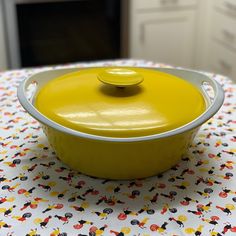 a yellow casserole dish sitting on top of a white tablecloth covered table