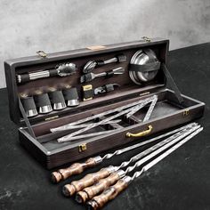 an assortment of kitchen utensils in a wooden case on a table with black background