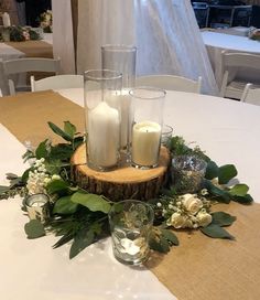 the centerpiece is decorated with candles and greenery on top of a wooden slice