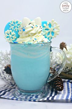 a cup filled with whipped cream and decorated cookies on top of blue glass mugs