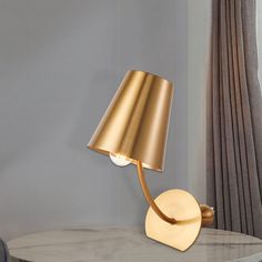 a gold lamp sitting on top of a table next to a gray chair and window