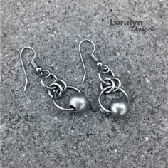 two silver balls are hanging from hooks on the concrete floor, one has been made to look like an earring