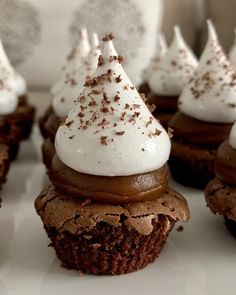 chocolate cupcakes topped with white frosting and sprinkles on a plate