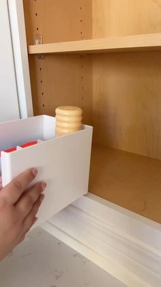 a person is opening the bottom drawer of a kitchen cabinet with some drawers in it