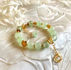 Beautiful jade and green cracked marbled beads bracelet with gold colored flowers. Rainbow butterfly charm. 100% hand made. Good gift for friends or family. Handmade Gold Jade Beaded Bracelets, Gold Beaded Bracelets With Jade Natural Stones, Gold Jade Beaded Bracelets With Natural Stones, Gold Jade Beaded Bracelets, Handmade Gold Aventurine Beaded Bracelets, Gold Aventurine Round Bead Bracelets, Gold Aventurine Beaded Bracelets, Gold Aventurine Bracelets As Gift, Gold Bracelet With Semi-precious Stone For Gift