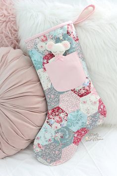 a pink and blue christmas stocking sitting on top of a pillow