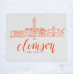 an orange and white business card with the name clemson university in front of a cityscape