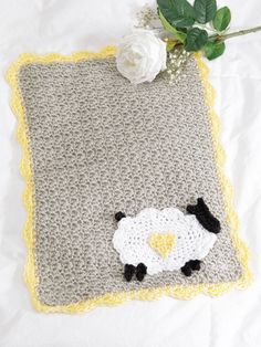 a crocheted blanket with a sheep on it and a flower in the corner