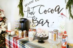 a table topped with lots of food next to a wall covered in christmas decorations and greenery