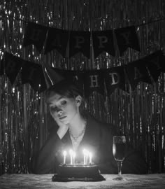 a woman sitting in front of a cake with candles