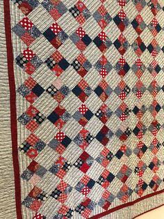 a red, white and blue quilt hanging on a wall