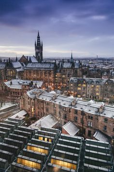 an aerial view of the city at night with snow on rooftops and buildings in the foreground