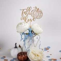 a cake topper that says fall in love with flowers and pumpkins on the table