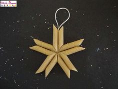 an ornament made out of wood sticks is hanging on a black surface with snowflakes in the background