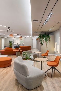 an office with orange and gray furniture in the middle of it's wood flooring