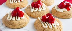 some cookies with raspberries on them are sitting on a plate next to other desserts