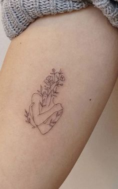 a woman's thigh with a small tattoo on her left leg and flowers in the middle