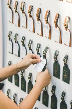 a woman is placing tags on a wall with many different types of luggage hangers