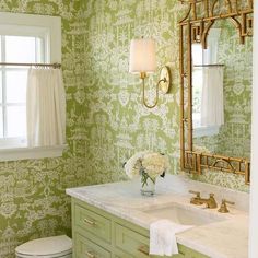 a bathroom with green wallpaper and gold fixtures