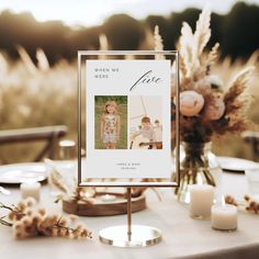 a table topped with a sign and candles next to some vases filled with flowers