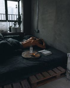 a person laying on top of a bed next to a bottle of alcohol and a tray