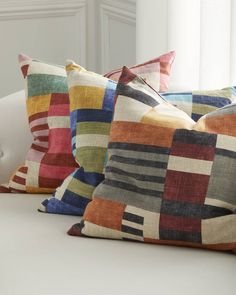 three colorful pillows sitting on top of a white couch