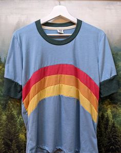 Santa Cruz Mountains Rainbow Camp Collection TShirt in Cloud Blue with Forest Green Accents This classic SCM design on a comfy classic shirt from Camp Collection: ∞Short sleeve crew neck ringer style tee, with long sleeves and shorter length ∞Rib neckband and sleeve bands ∞Slightly sheer vintage cloud blue jersey ∞Locker loop at back neck ∞60% cotton / 40% polyester ∞Fits true to size ∞Manufactured in the USA ∞Design by Present owner, Jackie Care - Machine wash cold, tumble dry low Retro Tri-blend Crew Neck T-shirt, Casual Color Block Crew Neck T-shirt, Summer Color Block Crew Neck T-shirt, Short Sleeve Color Block Cotton Shirt, Short Sleeve Cotton Color Block Shirt, Casual Cotton Color Block Shirt, Casual Color Block Cotton Shirt, Casual Blue Color Block Shirt, Retro Crew Neck Tops With Screen Print