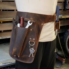 a man holding a leather tool belt with tools in it's pocket and two wrenches hanging from the back