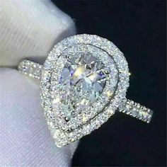 a close up of a diamond ring on a person's finger, with the center stone surrounded by smaller diamonds