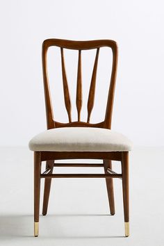 a wooden chair sitting on top of a white floor next to a wall with an upholstered seat