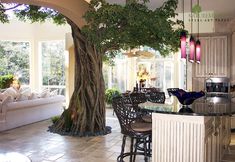 a kitchen and living room area with a tree in the middle of the center island