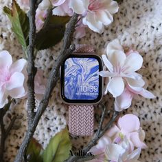 an apple watch sitting next to some pink flowers