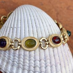 Estate/ vintage 14KT yellow gold Byzantine design, textured + cabochon, multi-gemstone link bracelet. Textured, shiny, and matte finishes on this piece. Slightly concave pieces with cabochon, amethyst, blue topaz, garnet, peridot, and citrine oval gemstones. Each gemstone measures: 7mm x 5mm; (8) total Rectangle byzantine + shiny open design links bracelet Measures 7.5", but fits shorter when clasped at the shorter length Weight: 22 grams Measures: 10mm wide Secure snap clasp Stamped 14K Great v Elegant Multicolor Cabochon Gemstones, Elegant Gold Cabochon Gemstones, Elegant Multi-stone Oval Cabochon Jewelry, Luxury Gold Oval Cabochon Gemstones, Oval Gold Gemstones With Accents, Gold Cabochon Gemstones For Formal Occasions, Formal Gold Cabochon Gemstones, Gold Metal Bracelet With Cabochon, Gold Jewelry With Gemstone Accents In Oval Cabochon