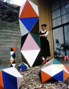 a woman standing in front of an art sculpture that looks like it is made out of geometric shapes