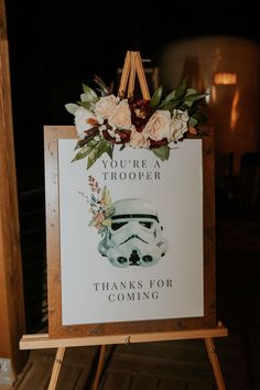 a star wars themed wedding sign with flowers and a stormtrooper on it's easer