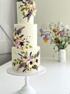 a three tiered cake with flowers painted on it