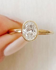 a close up of a person's hand holding a diamond ring