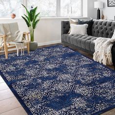 a living room area with a couch, chair and rug in blue tones on the floor