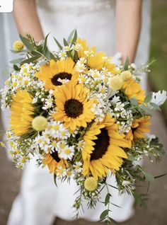 a bride holding a bouquet of sunflowers and daisies