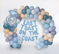 a balloon arch with the words'last toast on the coast'written in blue