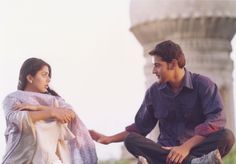 a man and woman sitting next to each other in front of a stone structure with columns