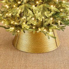 a small christmas tree in a gold tinsel pot with lights on the top and bottom