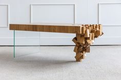 a wooden bench made out of pieces of wood and glass sitting in front of a white wall