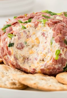 a cheese ball on top of crackers is sitting on a plate with other snacks