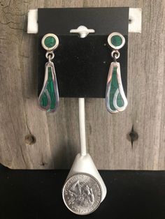 Malachite and Sterling Silver Earrings Southwestern Beautiful green Malachite is inlayed into Sterling Silver to create these gorgeous Southwestern-style earrings. The earrings come in two pieces connected together to create an attractive dangle drop style. These gorgeous earrings are finished off with post backs. They are stamped on the backs with the artisan's number, 925 (Sterling) and Mexico, denoting their country of excellent craftmanship. Length: 1-1/2 inches Width: 1/2 inch Weight: 12 gr Southwestern Green Dangle Earrings, Handmade Southwestern Green Earrings, Southwestern Green Teardrop Earrings, Southwestern Green Sterling Silver Earrings, Green Southwestern Style Jewelry With Inlay, Nickel-free Green Southwestern Jewelry, Green Teardrop Southwestern Jewelry, Southwestern Style Green Inlay Jewelry, Artisan Green Jewelry For Pierced Ears