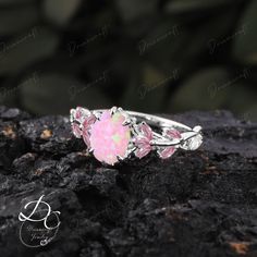 a pink opal ring sitting on top of a rock